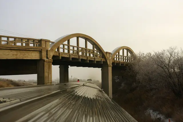 Via Rail's The Canadian passing under an arched concrete bridge